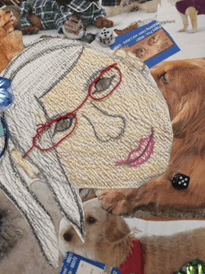 Close-up of a collage that a child created that includes a self-portrait drawing, and images of various dogs.