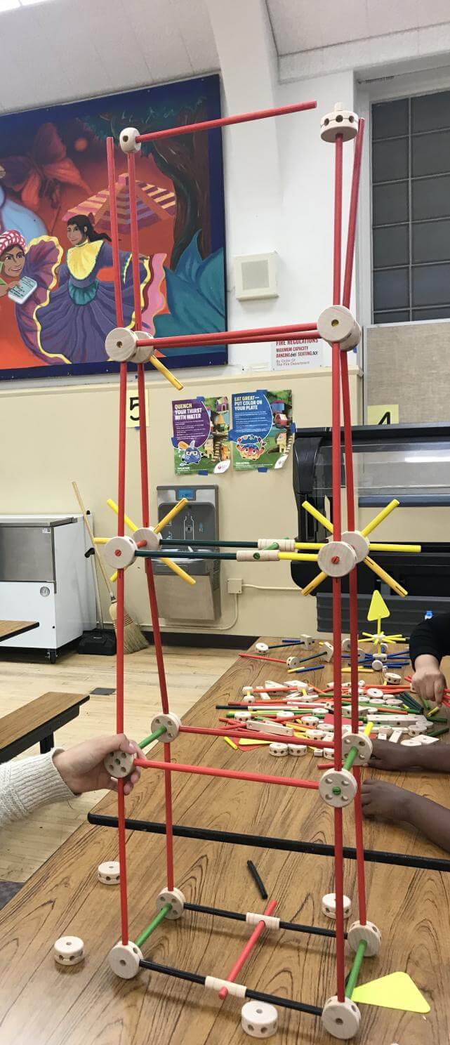Close-up of a structure being put together by children using tinker toys.