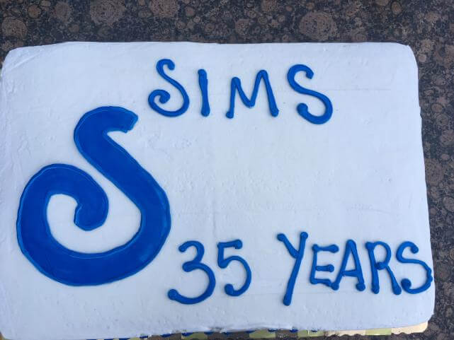 Close-up of sheet cake with white and blue frosting that says, "SIMS 35 years".